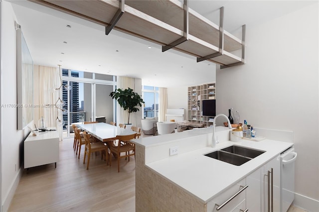 kitchen with light wood-style flooring, a sink, open floor plan, light countertops, and baseboards