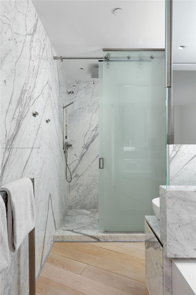 bathroom featuring a marble finish shower and vanity