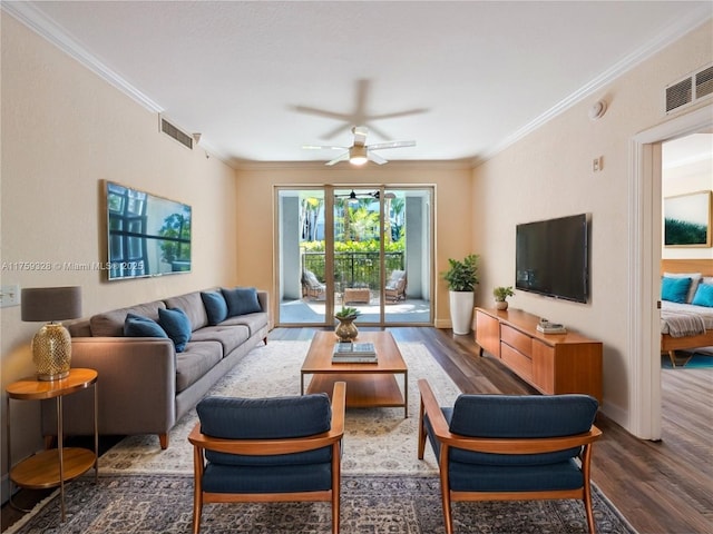 living area featuring baseboards, wood finished floors, visible vents, and ornamental molding