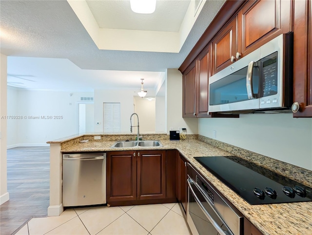 kitchen featuring light stone counters, visible vents, a peninsula, a sink, and stainless steel appliances