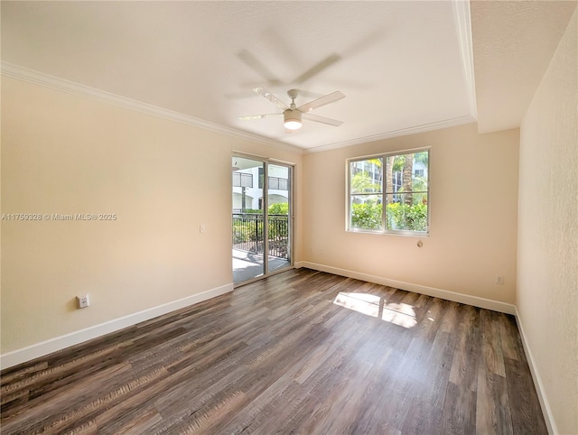 spare room with baseboards, crown molding, dark wood-type flooring, and a ceiling fan