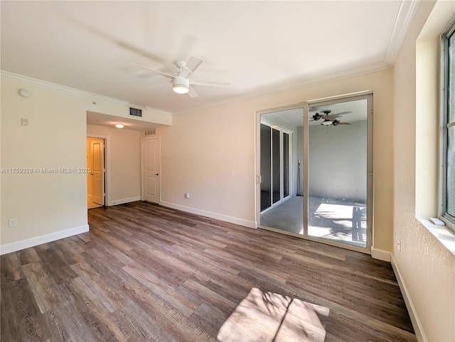 empty room with visible vents, wood finished floors, baseboards, and ornamental molding