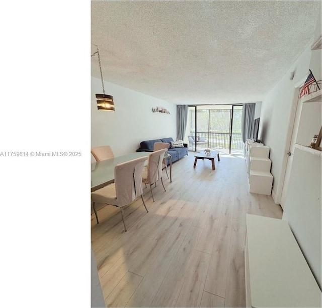 living area featuring floor to ceiling windows, light wood-style flooring, and a textured ceiling