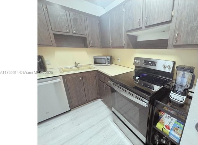 kitchen featuring gray cabinetry, a sink, light countertops, under cabinet range hood, and appliances with stainless steel finishes