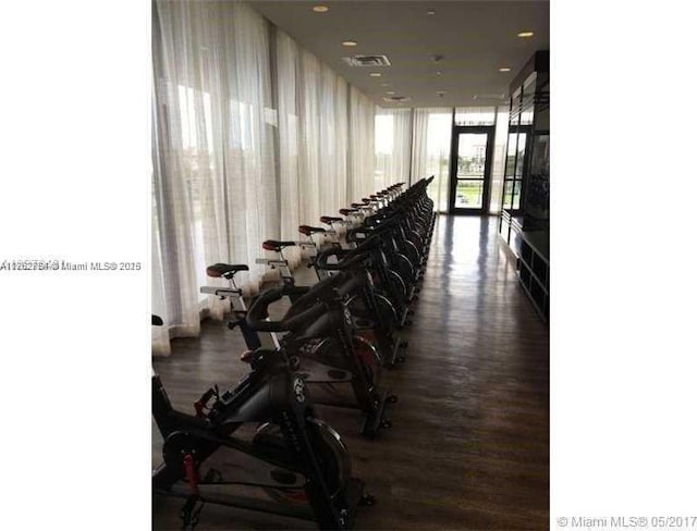 exercise room with a wall of windows, wood finished floors, and visible vents