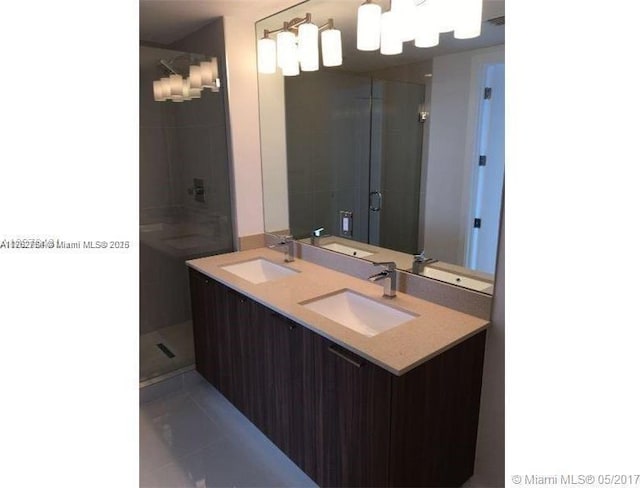 full bathroom with double vanity, a shower stall, and a sink