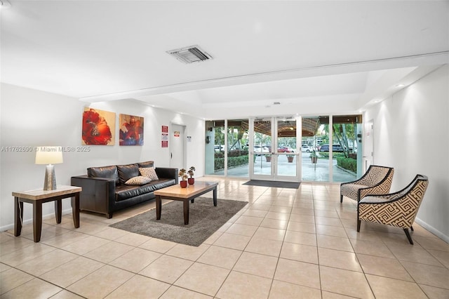 living room featuring light tile patterned floors, french doors, visible vents, and baseboards