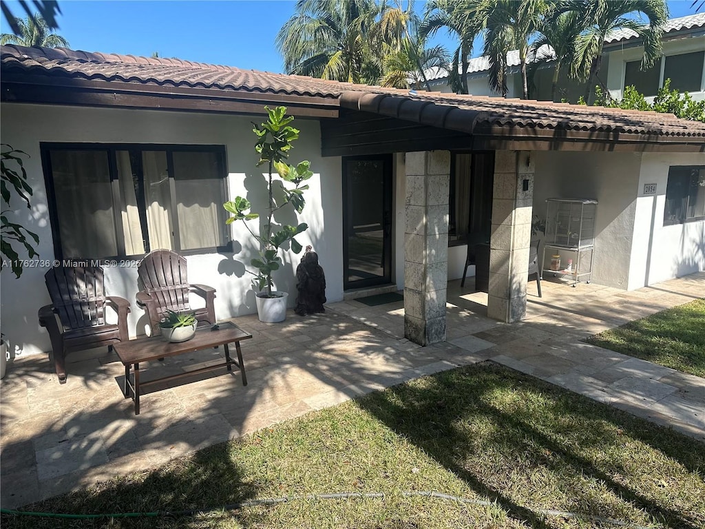 rear view of property featuring stucco siding, a patio, and a tile roof