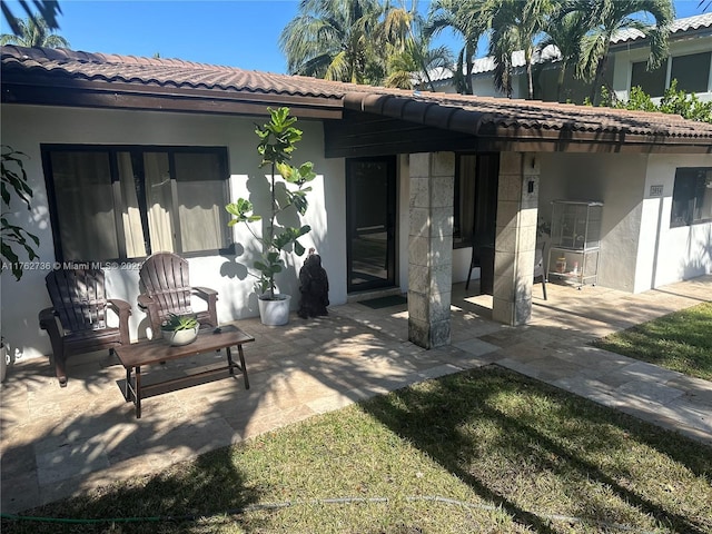 rear view of property featuring stucco siding, a patio, and a tile roof