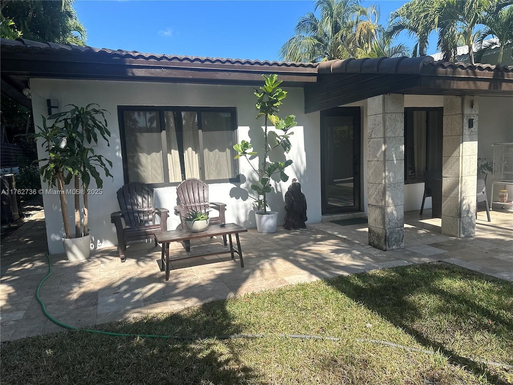 rear view of property featuring stucco siding, a patio, and a tiled roof