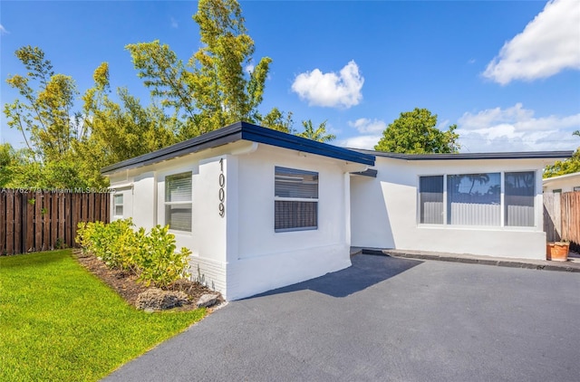 view of front of home featuring a front lawn, fence, and stucco siding