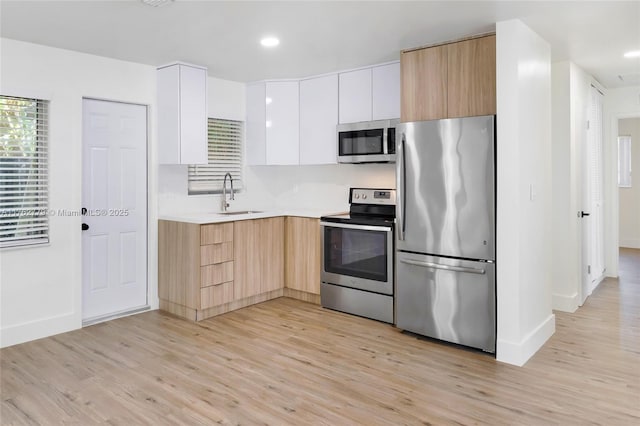 kitchen featuring a sink, light brown cabinetry, light countertops, stainless steel appliances, and modern cabinets