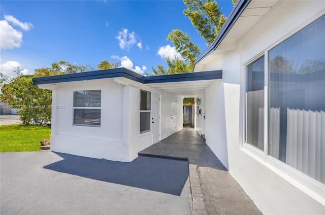 view of exterior entry featuring stucco siding and a patio