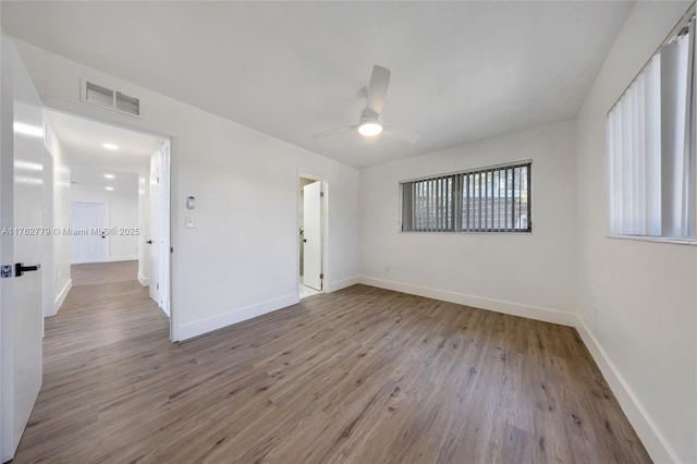 spare room with visible vents, a ceiling fan, baseboards, and wood finished floors