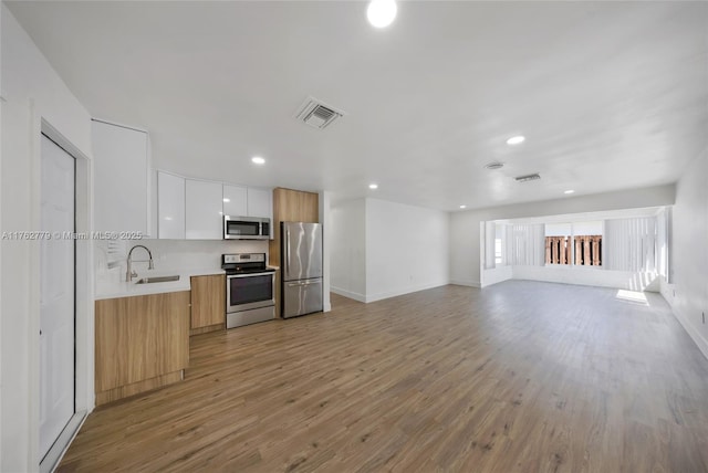 kitchen with visible vents, light countertops, stainless steel appliances, modern cabinets, and a sink