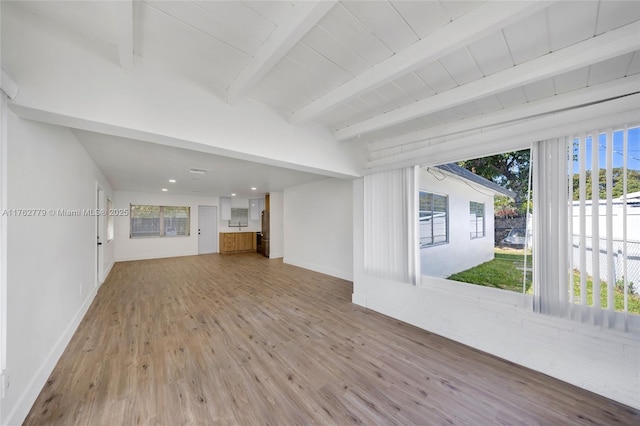 unfurnished living room with beam ceiling, wood finished floors, and baseboards