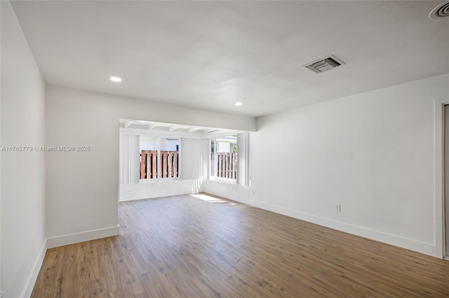 empty room featuring recessed lighting, wood finished floors, visible vents, and baseboards