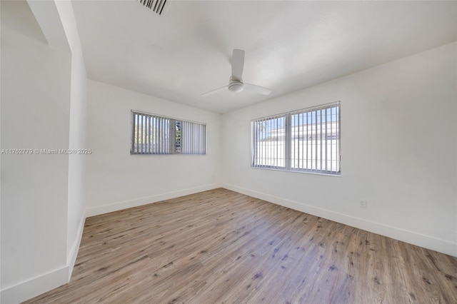 unfurnished room with visible vents, a ceiling fan, baseboards, and wood finished floors