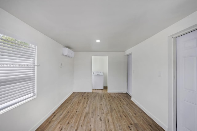 unfurnished room featuring wood finished floors, baseboards, washer / clothes dryer, recessed lighting, and an AC wall unit