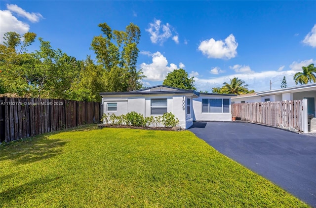 view of front facade featuring stucco siding, a front yard, and fence