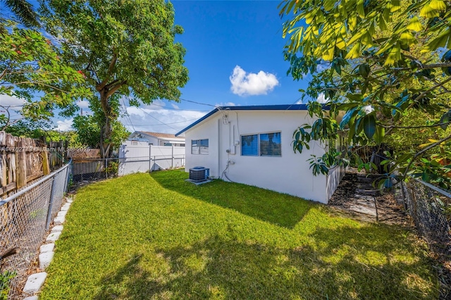 exterior space with a fenced backyard, central air condition unit, stucco siding, and a yard