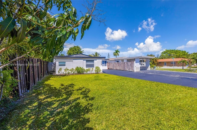 ranch-style house with aphalt driveway, stucco siding, a front yard, and fence