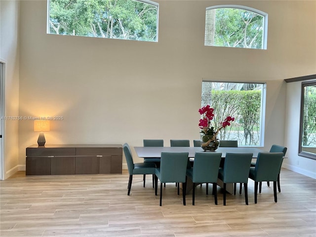 dining room with baseboards, a high ceiling, and light wood finished floors