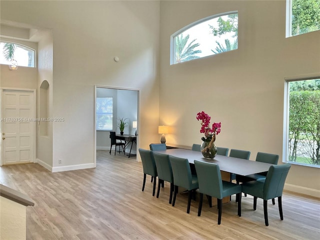 dining area with light wood finished floors, plenty of natural light, arched walkways, and baseboards