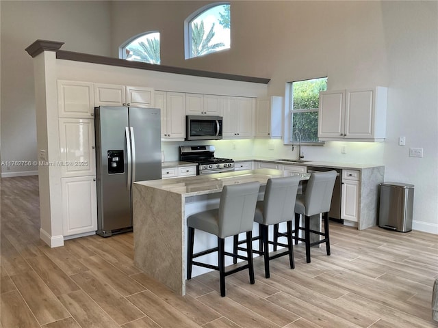 kitchen featuring a sink, appliances with stainless steel finishes, a center island, and white cabinetry