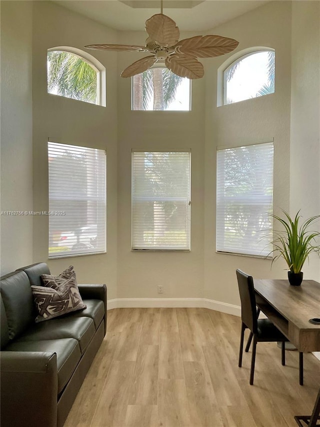 interior space featuring a wealth of natural light, light wood-style flooring, and a towering ceiling