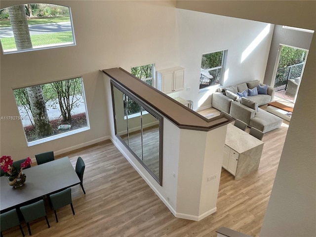 stairs with plenty of natural light, wood finished floors, and a towering ceiling