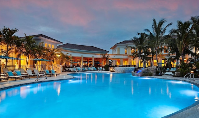 pool at dusk featuring a patio and a community pool