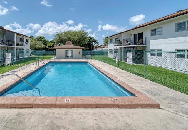 pool with a yard, a patio, an outdoor structure, and fence