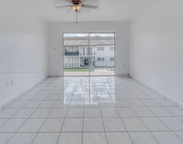 empty room featuring light tile patterned floors, baseboards, a textured ceiling, and ceiling fan