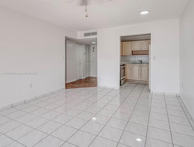 interior space with light tile patterned floors, visible vents, a textured ceiling, and a sink