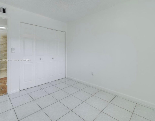 unfurnished bedroom featuring a closet, baseboards, visible vents, and light tile patterned flooring