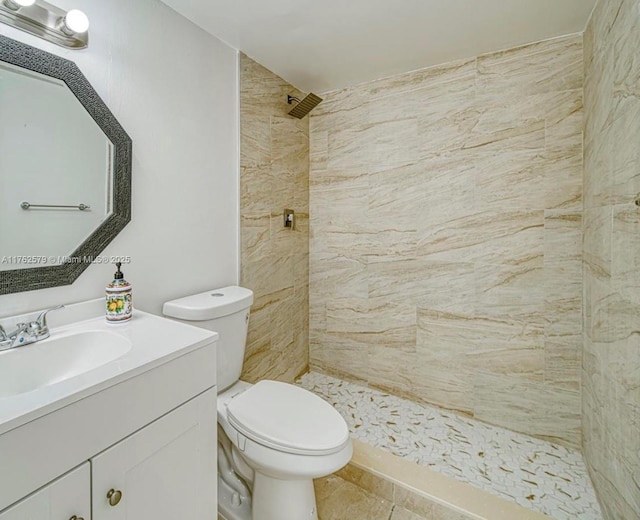 bathroom featuring vanity, toilet, and a tile shower