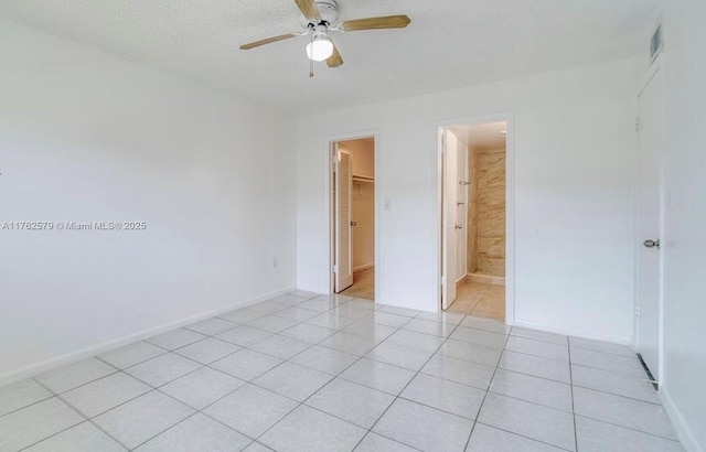 unfurnished bedroom featuring a walk in closet, visible vents, a textured ceiling, a closet, and light tile patterned floors