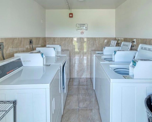 shared laundry area with tile walls and independent washer and dryer