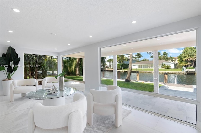 living room featuring recessed lighting, a water view, and a textured ceiling