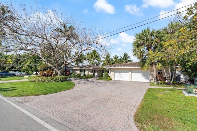 view of front of house with stucco siding, a front lawn, a tile roof, decorative driveway, and a garage