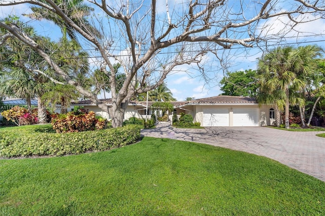 view of front of home featuring a front yard, an attached garage, stucco siding, a tiled roof, and decorative driveway