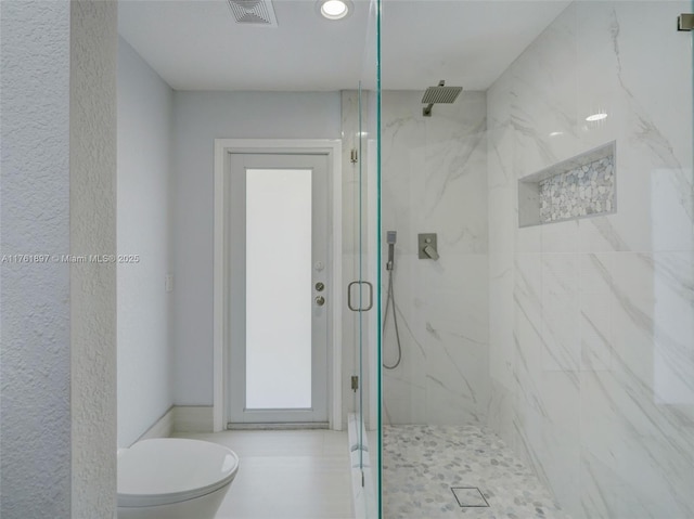 full bath featuring a marble finish shower, visible vents, toilet, and a textured wall