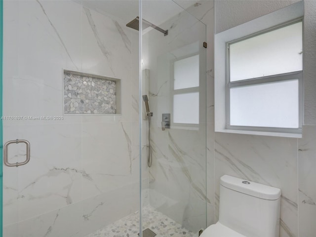 bathroom featuring a marble finish shower and toilet