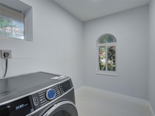 clothes washing area with laundry area, washer / dryer, and baseboards