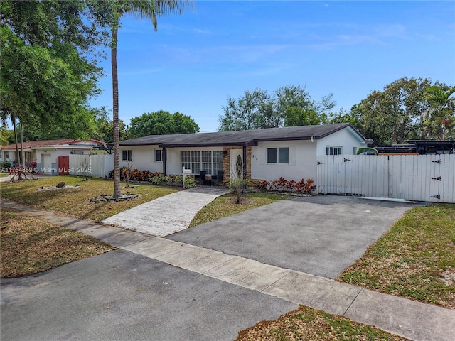 ranch-style house with a front yard, a gate, fence, and stucco siding