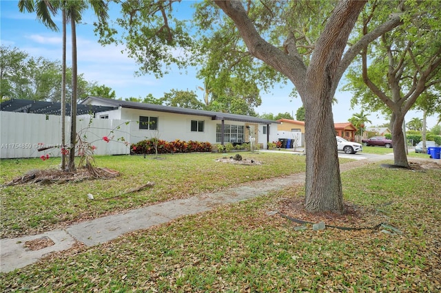 ranch-style home with a front lawn and fence