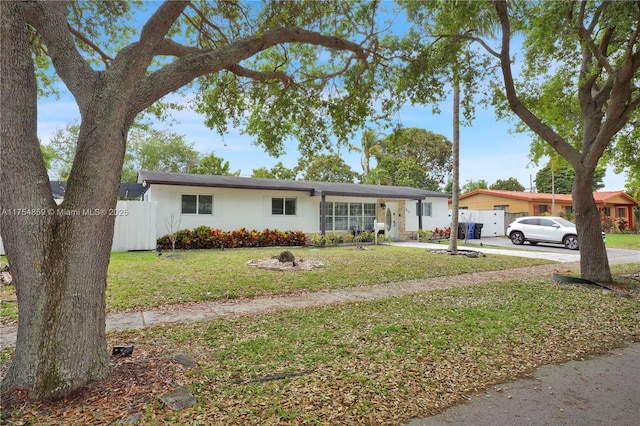 single story home featuring a front lawn, concrete driveway, fence, and stucco siding