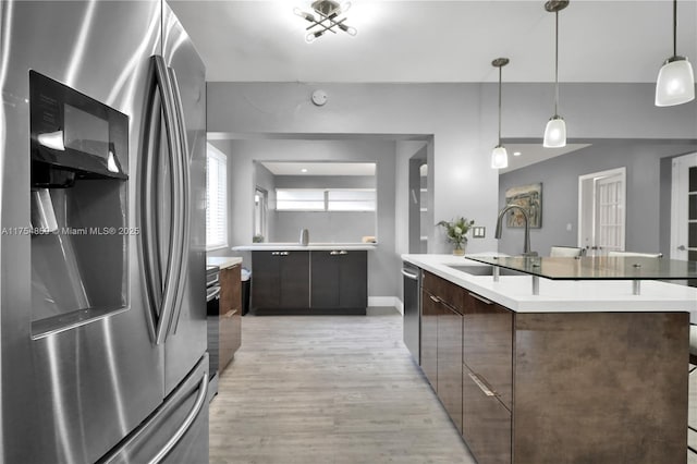 kitchen featuring modern cabinets, light wood-style flooring, a sink, stainless steel appliances, and light countertops