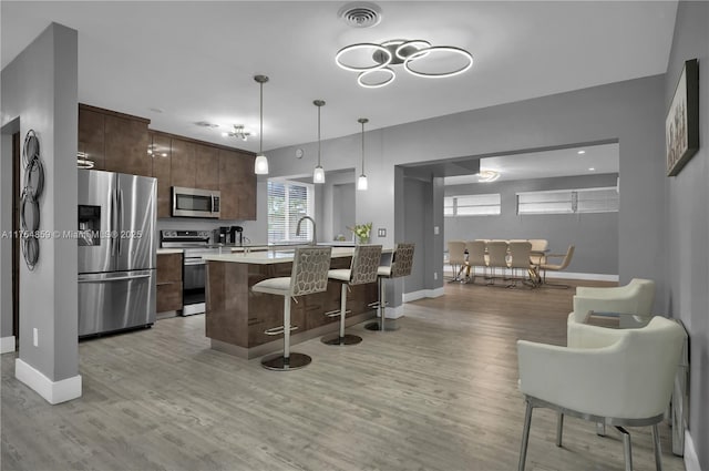 kitchen with visible vents, light countertops, appliances with stainless steel finishes, a kitchen breakfast bar, and modern cabinets